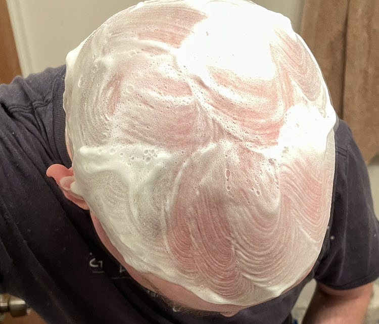 A man getting ready to shave his lathered head